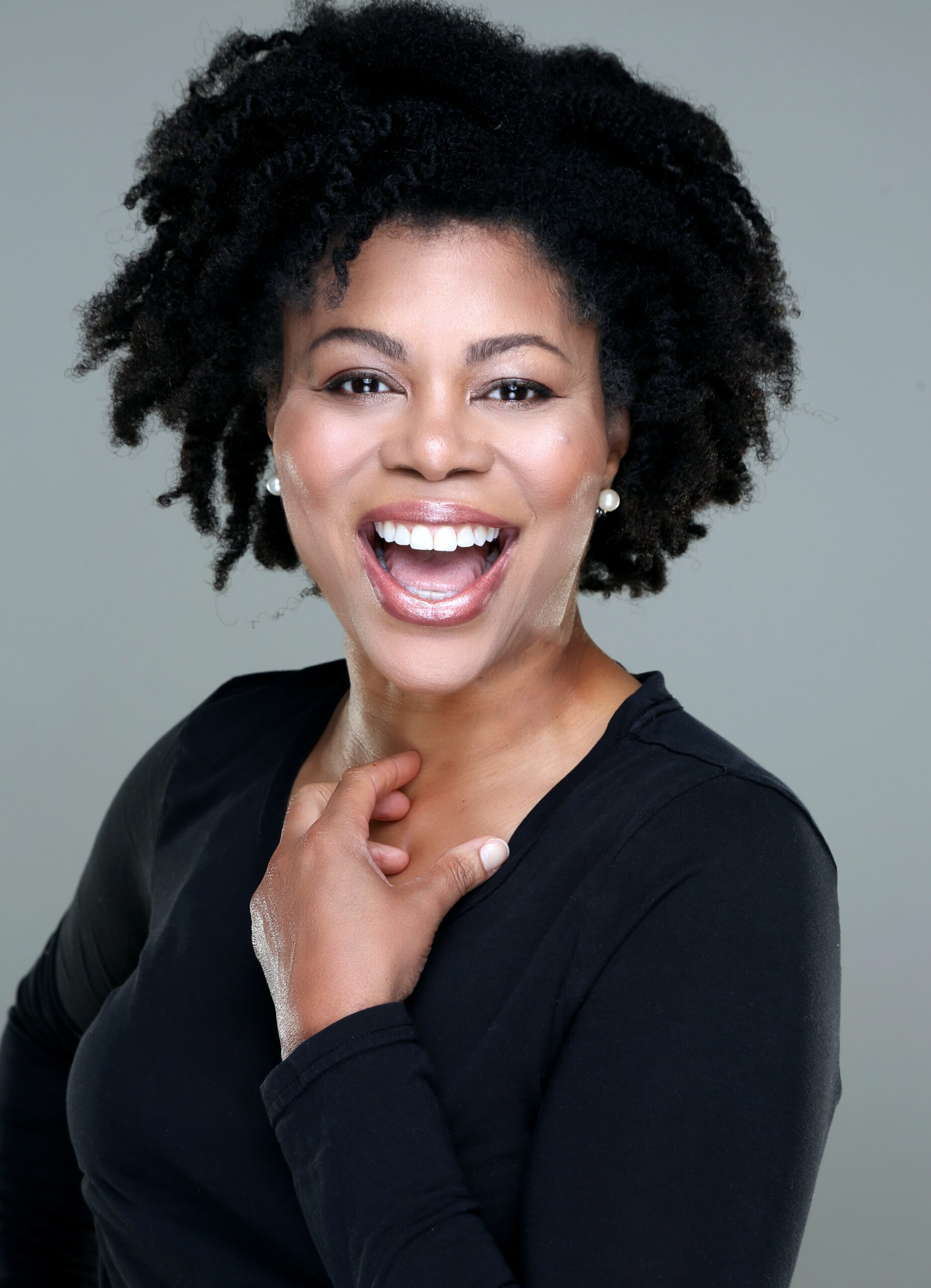 A joyful woman with natural hair laughing brightly.